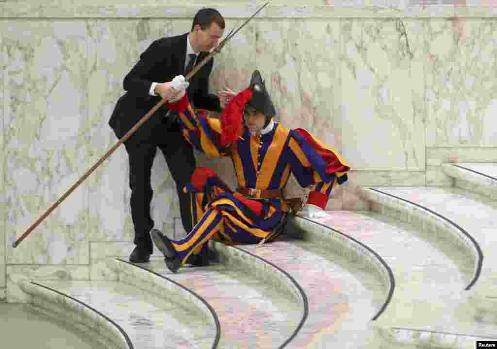 A Swiss Guard, who fell ill, is helped as Pope Francis leads the weekly audience at Vatican's Paul VI Audience Hall.