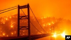 En esta imagen tomada con una velocidad de obturación lenta, las brasas iluminan una ladera detrás del puente Bidwell Bar mientras el Bear Fire arde en Oroville, California, el miércoles 9 de septiembre de 2020.