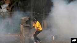 A demonstrator hides behind a barricade during clashes with the Bolivarian National Guard, at El Hatillo municipality outside Caracas, Venezuela, Tuesday, May 2, 2017.