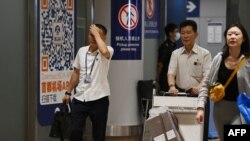 Two North Korean men walk through the arrivals section at Beijing Capital Airport after the arrival of Air Koryo flight JS151 on Aug. 22, 2023.