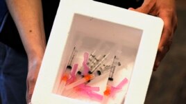 A nurse holds a cooler of COVID-19 vaccine at the Macon County Health Department in Tuskegee, Ala., Monday, Jan. 25, 2021.
