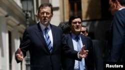 Spain's Prime Minister Mariano Rajoy (L) reacts to a question from a reporter as he leaves after a session at the Senate in Madrid, Aug. 1, 2013.