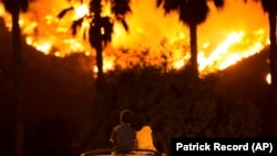 King Bass, 6, left, sits and watches the Holy Fire burn from on top of his parents' car as his sister Princess, 5, rests her head on his shoulder in Lake Elsinore, California.