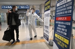 Seorang petugas (tengah) mengenakan APD, memandu seorang pendatang di aula kedatangan Bandara Internasional Incheon di tengah kekhawatiran yang meningkat terkait varian Omicron COVID-19, 30 November 2021. (Jung Yeon-je / AFP)
