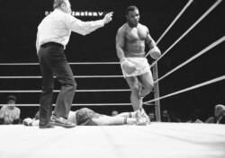 Wasit Arthur Mercante menunjukkan jalan ke sudut netral untuk Mike Tyson (kana) setelah dia menjatuhkan Steve Zouski di ronde ketiga dari sepuluh ronde pertandingan tinju di Nassau Coliseum di Uniondale, NY, 11 Maret 1986. (AP Photo/Ray Stubblebine, File)