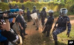 A line of riot police prevent the media from approaching Uganda's main opposition leader Kizza Besigye as he tries to leave his house in Kasangati, Uganda, Feb. 22, 2016.