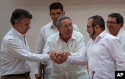 Cuba's President Raul Castro, center, encourages Colombian President Juan Manuel Santos, left, and Commander the Revolutionary Armed Forces of Colombia or FARC, Timoleon Jimenez, known as "Timochenko," to shake hands, in Havana, Cuba, Sept. 23, 2015.