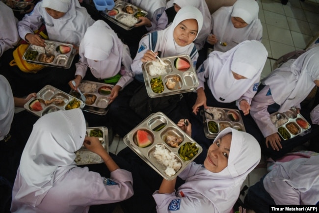 Siswa SMP Negeri 12 Cimahi, Jawa Barat, menikmati makan siang pada hari pertama program makan gratis, 6 Januari 2025. (Foto: Timur Matahari/AFP)