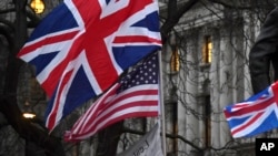 Pendukung Brexit memegang bendera Inggris dan AS di London, Jumat, 31 Januari 2020. (Foto: AP)