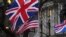 Pendukung Brexit memegang bendera Inggris dan AS di London, Jumat, 31 Januari 2020. (Foto: AP)