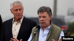 Colombia's President Juan Manuel Santos speaks while flanked by U.S. Defense Secretary Chuck Hagel (L) after a meeting at the military airport in Bogota October 10, 2014. Hagel began a trip to Latin America on Thursday, and will be visiting Colombia, Peru