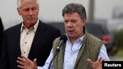 Colombia's President Juan Manuel Santos speaks while flanked by U.S. Defense Secretary Chuck Hagel (L) after a meeting at the military airport in Bogota October 10, 2014. Hagel began a trip to Latin America on Thursday, and will be visiting Colombia, Peru