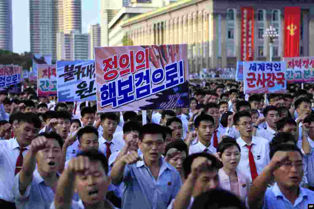 평양시 군중집회에서 참가자들이 &#39;정의의 핵보검으로!&#39; &#39;세계적인 군사강국&#39; 등 구호가 적힌 플랜카드를 들고 행진하고 있다.