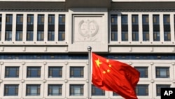 FILE - A Chinese national flag billows in front of a building of Shandong Province Supreme People's Court in Jinan.