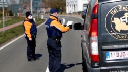 Polisi Belgia mengenakan masker saat memeriksa dokumen pengendara mobil di perbatasan Belgia-Belanda di tengah pandemi Covid-19, di Meersel-Dreef, Belgia, Maret 2020. (Foto: dok).