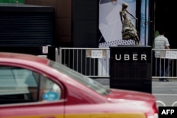 FILE - A taxi passes by an Uber station outside a shopping mall in Beijing on August 1, 2016.