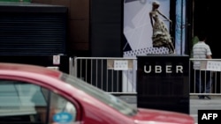 A taxi passes by an Uber station outside a shopping mall in Beijing. Uber is planning on bringing its UberEats to 22 more cities, but it's unclear if Beijing is among them. 