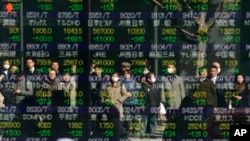 People are reflected on an electronic stock indicator of a securities firm in Tokyo, Tuesday, Feb. 6, 2018.