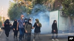 In this Oct. 1, 2022, photo taken by an individual not employed by the Associated Press and obtained by the AP outside Iran, tear gas is fired to disperse protesters in front of the Tehran University, Iran.