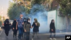 In this Oct. 1, 2022, photo taken by an individual not employed by the Associated Press and obtained by the AP outside Iran, tear gas is fired to disperse protestors in front of the Tehran University, Iran.