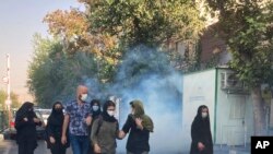 In this Oct. 1, 2022, photo taken by an individual not employed by the Associated Press and obtained by the AP outside Iran, tear gas is fired to disperse protestors in front of the Tehran University, Iran.