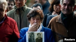 Carmen Benito sostiene una imagen de su tío durante la exhumación de una tumba que sostiene personas asesinadas por el ejército de Franco.