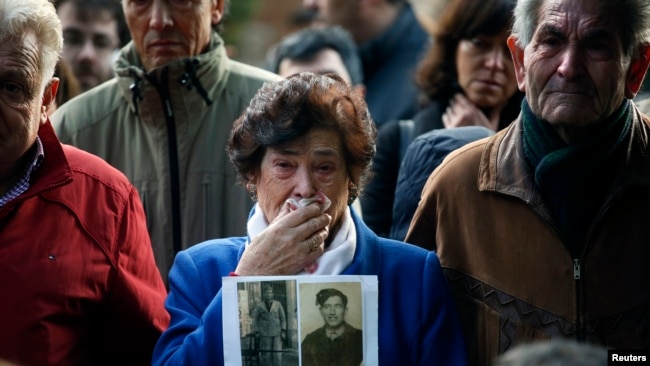 Carmen Benito sostiene una imagen de su tío durante la exhumación de una tumba que sostiene personas asesinadas por el ejército de Franco.