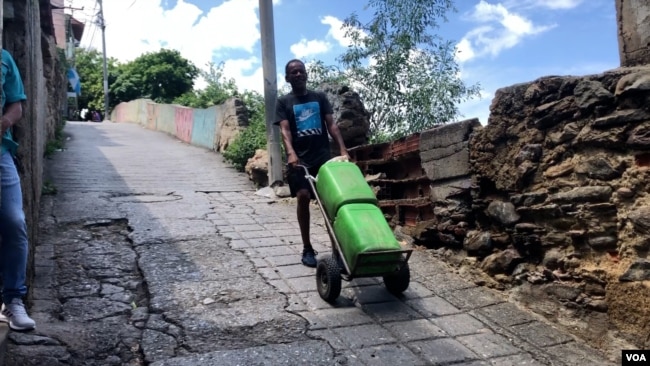 Wilmer Escobar, de 50 años, empuja una carretilla con unos pesados tanques por un empinado callejón en La Guaira, Venezuela.