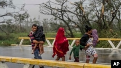 A family walks in the rain in search of shelter after Hurricane Ian hit Pinar del Rio, Cuba, Sept. 27, 2022. Officials set up shelters, evacuated people, rushed in emergency personnel and took steps to protect crops in the nation's main tobacco-growing region.