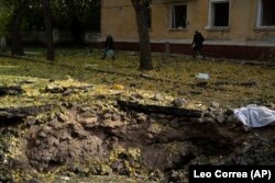 People walk past a crater created by an explosion after a Russian attack in Kramatorsk, Ukraine, Thursday, Sept. 29, 2022 (AP Photo/Leo Correa)