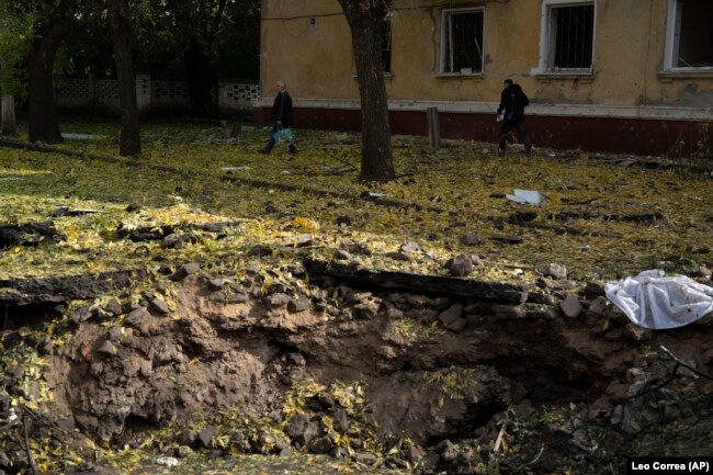 People walk past a crater created by an explosion after a Russian attack in Kramatorsk, Ukraine, Thursday, Sept. 29, 2022 (AP Photo/Leo Correa)