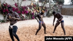 Des lutteurs se couvrent de sable alors qu'ils se préparent à commencer leur programme d'entraînement à Petit Mbao, au Sénégal, le 29 mars 2021.