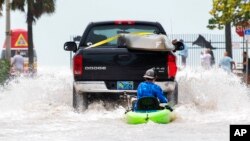 Sebuah truk menarik seorang pria di atas kayak di jalan dataran rendah yang terdampak banjir yang dipicu oleh Badai Ian, di Key West, Florida, Rabu sore, 28 September 2022. (AP/Mary Martin)