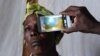 FILE - A technician scans the eye of a woman with a smartphone application, in Kianjokoma village, near Kenya's lakeside town of Naivasha, Aug. 28, 2013.