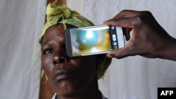 FILE - A technician scans the eye of a woman with a smartphone application, in Kianjokoma village, near Kenya's lakeside town of Naivasha, Aug. 28, 2013.