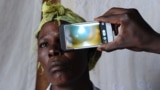 FILE - A technician scans the eye of a woman with a smartphone application, in Kianjokoma village, near Kenya's lakeside town of Naivasha, Aug. 28, 2013.
