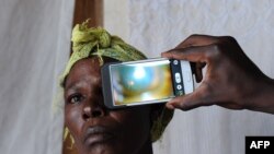 FILE - A technician scans the eye of a woman with a smartphone application, in Kianjokoma village, near Kenya's lakeside town of Naivasha, Aug. 28, 2013.