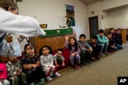 The Rev. Anna Silco, a co-pastor of the Shishmaref Lutheran Church with her husband, Aaron, interacts with children while showing them mustard seeds during a Sunday service in Shishmaref, Alaska, Sunday, Oct. 2, 2022.