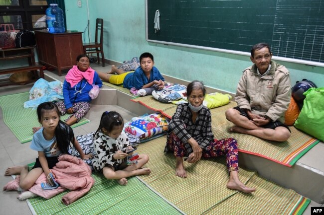 People sit in a school being used as a shelter during Typhoon Noru in Hoi An on September 27, 2022. - Vietnam has tried to evacuate people ahead of the arrival of typhoon Noru, one of the biggest to make landfall in the country, officials said on September 27. (Photo by Nhac NGUYEN / AFP)