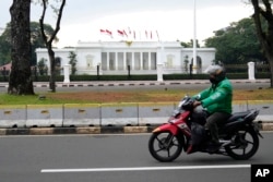 Seorang pengendara motor melewati Istana Merdeka di Jakarta, Indonesia, Selasa, 25 Oktober 2022. (AP/Dita Alangkara)