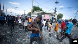 FILE - A protester carries a piece of wood simulating a weapon during a protest demanding the resignation of Prime Minister Ariel Henry, in the Petion-Ville area of Port-au-Prince, Haiti, Oct. 3, 2022.