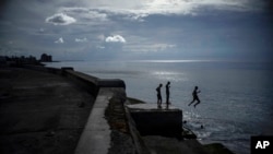 FILE - Boys spend the afternoon jumping into the water from the sea wall in Havana, Cuba, Sept. 15, 2022.