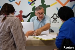 FILE - Ukrainian refugee Ihor Ostrovskyi helps newly arrived Ukrainian refugees at a support center in Lisbon, Portugal, Sept. 27, 2022.
