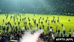 Tangkapan layar video AFPTV yang diambil pada 1 Oktober 2022 menunjukkan gas air mata yang disemprotkan di kerumunan saat suporter berlarian di lapangan setelah pertandingan sepak bola antara Arema FC dan Persebaya Surabaya di Stadion Kanjuruhan di Malang