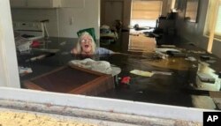 In this photo provided by Johnny Lauder, Lauder's mother, Karen Lauder, 86, is submerged nearly to her shoulders in water that has flooded her home, in Naples, Fla., Wednesday, Sept. 28, 2022, following Hurricane Ian.