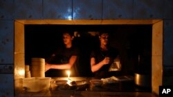 Staff at an eatery work by candle light after a failure in Bangladesh's national power grid plunged much of the country into a blackout in Dhaka, Bangladesh, Oct.4, 2022. 