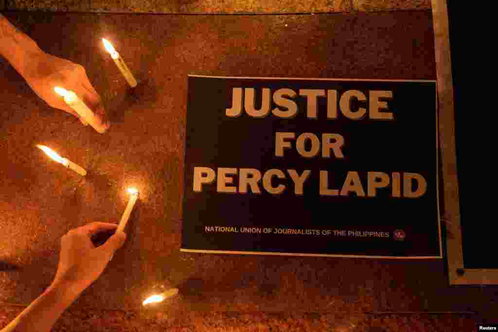 Reporters and activists light candles for killed Filipino radio journalist Percival Mabasa during an indignation rally, in Quezon City, Philippines.