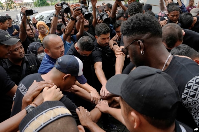 Para pemain dan ofisial klub Arema FC melakukan salat di luar Stadion Kanjuruhan di mana banyak suporter kehilangan nyawa akibat terinjak-injak Sabtu malam di Malang, Senin, 3 Oktober 2022. (Foto: AP)
