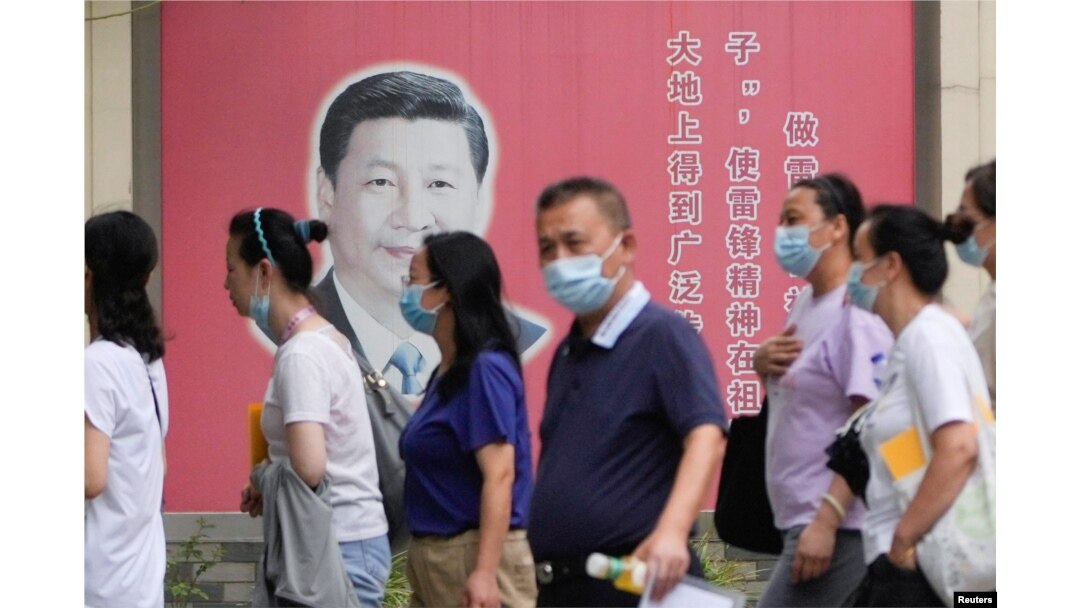Orang-orang yang memakai masker melewati potret Presiden China Xi Jinping, menyusul wabah COVID-19, di Shanghai, China, 31 Agustus 2022. (Foto: REUTERS/Aly Song)