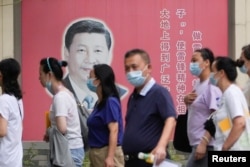 Orang-orang yang memakai masker melewati potret Presiden China Xi Jinping, menyusul wabah COVID-19, di Shanghai, China, 31 Agustus 2022. (Foto: REUTERS/Aly Song)